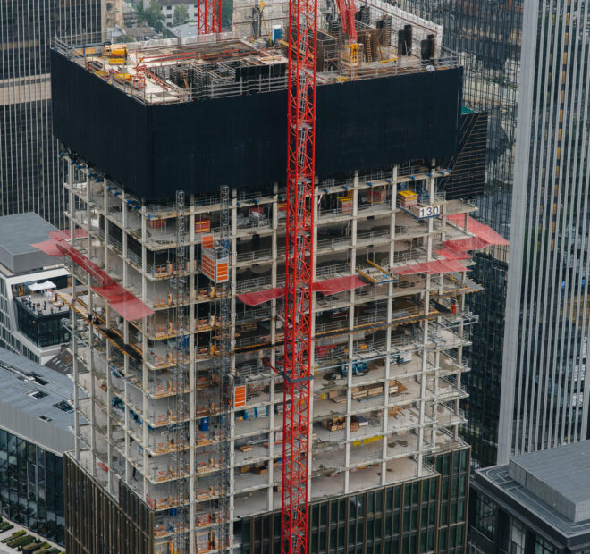 Construction of a modern high-rise skyscraper with cranes in the center of the metropolis. Construction